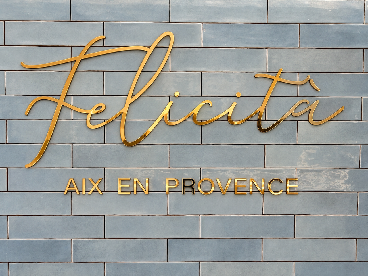 L'enseigne dorée Félicità sur la céramique bleu ciel du bar